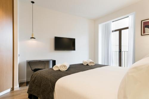 a bedroom with a bed and a tv on the wall at Vale Suites in Barcelona