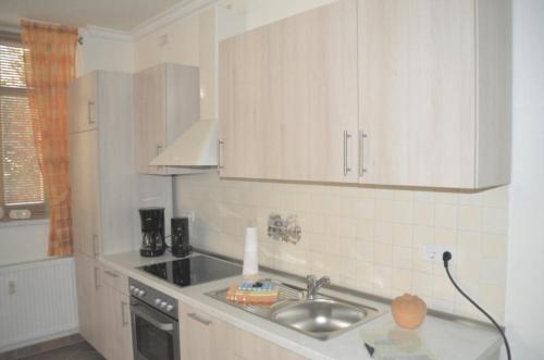 a kitchen with white cabinets and a sink at Ferienwohnung am Schloss Rochlitz in Rochlitz