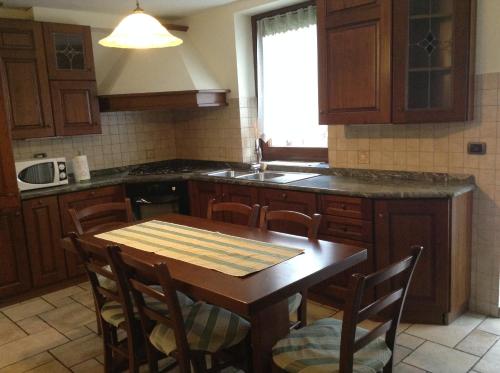a kitchen with a wooden table with chairs and a sink at Relais du Berger in Aosta