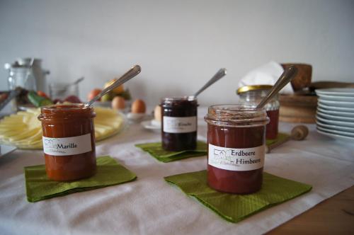 three jars of jam on a table with plates at Biohof Ebenbauer in Waidhofen an der Ybbs