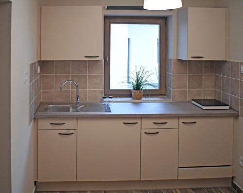 a kitchen with a sink and a window at VATUS Apartmanház Vác in Vác