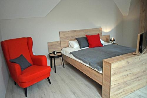 a bedroom with a bed and a red chair at VATUS Apartmanház Vác in Vác