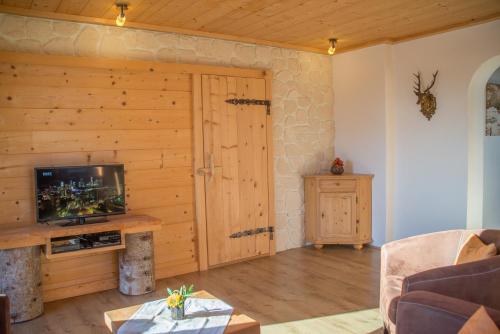 a living room with a tv and a wooden door at Apartments Landhaus Sonnheim in Lofer