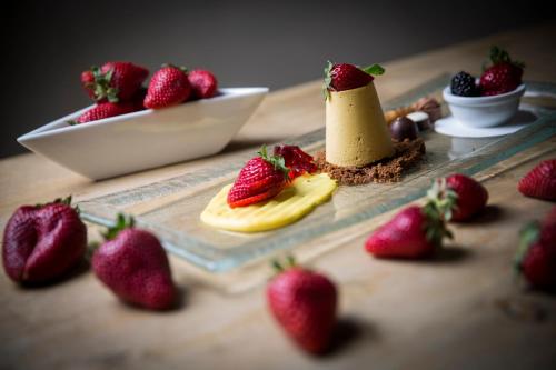 a table with strawberries and a miniature lighthouse on a plate at Olympic SPA Hotel - Adults Only in Vigo di Fassa