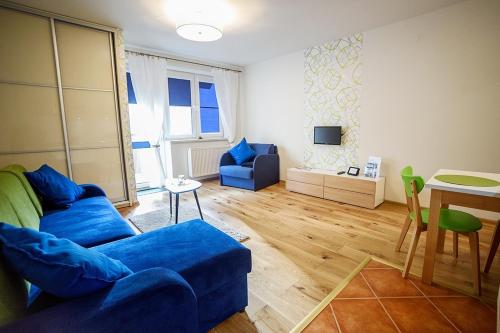 a living room with a blue couch and a table at Apartamenty Sun & Snow Park Sportowy in Krynica Zdrój