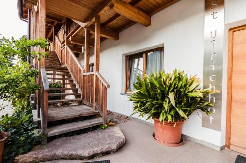 a house with wooden stairs and potted plants at St. Ulrichhof in Lana