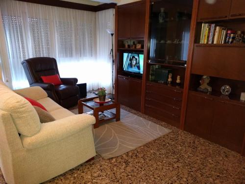 sala de estar con sofá, silla y TV en Ca la Xesca, en Olot