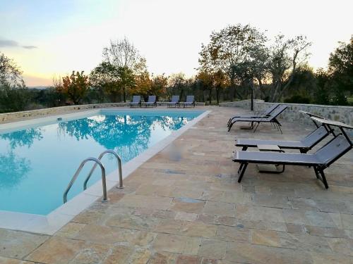 a swimming pool with benches and chairs next to it at Borgo Argiano in Castelnuovo Berardenga
