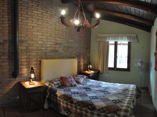 a bedroom with a bed and a brick wall at Cabañas Mi Refugio in Villa Giardino