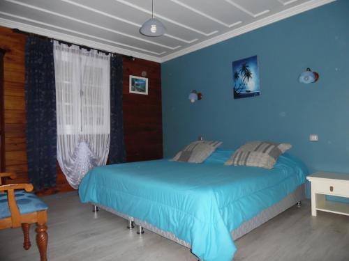 a blue bedroom with a bed and a window at Le Cimendef in Salazie