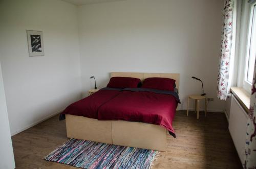 a bedroom with a large bed with red sheets at Ferienwohnung 2 Kormoran in Sagard