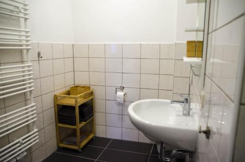 a white bathroom with a sink and a shelf at Ferienwohnung 2 Kormoran in Sagard