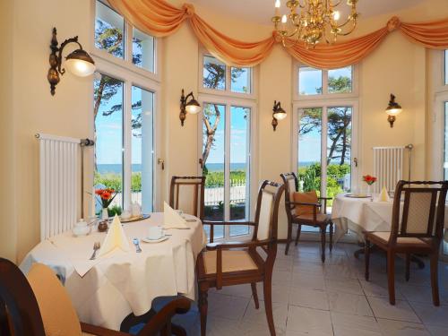 jadalnia ze stołami, krzesłami i oknami w obiekcie Villa Desny w mieście Bansin