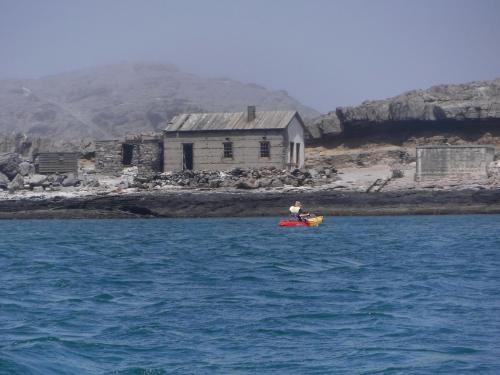 a person in a kayak in the water in front of a house at Alte Villa Boutique Hotel in Lüderitz
