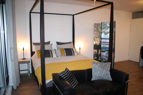 The Water Studio في أمستردام: غرفة نوم مع سرير كبير ومظلة وأريكة