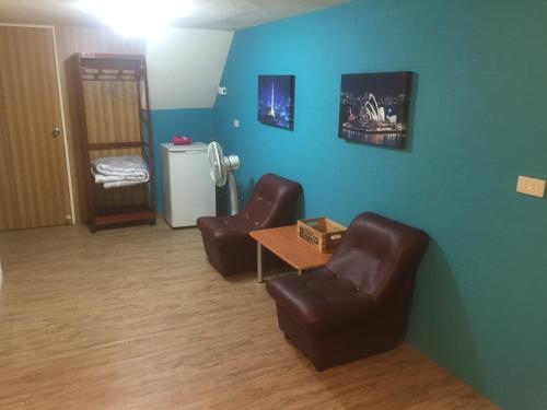 a living room with two leather chairs and a table at Traveler Station in Kaohsiung