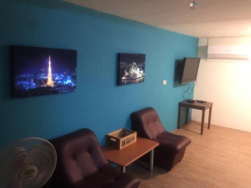 a living room with two chairs and a flat screen tv at Traveler Station in Kaohsiung