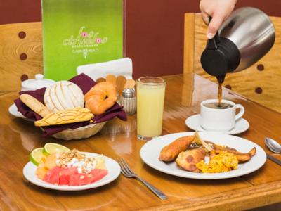a table with plates of food and a person pouring coffee at Hotel Madan Cárdenas in Cárdenas
