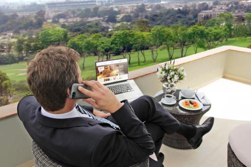 a man sitting on a balcony talking on a cell phone at Casa Andina Premium Golf Los Incas in Lima