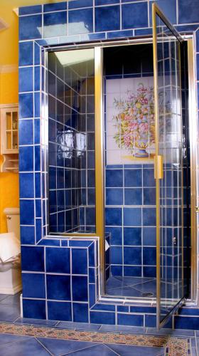 a blue tiled bathroom with a glass door at L'Auberge Provencale Inn & Restaurant in Boyce