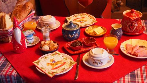 uma mesa com uma toalha de mesa vermelha com alimentos e bebidas em Chambres d'Hôtes Chez Mado Ottrott em Ottrott