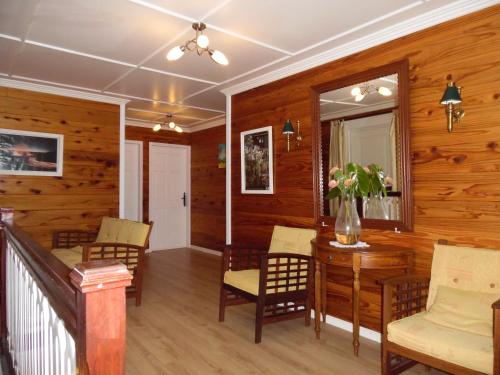 a living room with wooden walls and a table and chairs at Le Cimendef in Salazie
