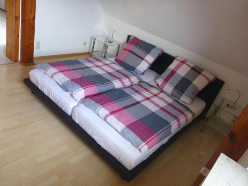 a bed with a plaid blanket and pillows on it at Ferienwohnung Schorfheide in Joachimsthal