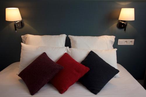 a bed with white pillows and red and black pillows at La Villa en L'île - 2 Piscines & Spa in Noirmoutier-en-l'lle