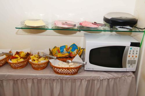 eine Mikrowelle auf einem Tisch mit Körben voller Essen in der Unterkunft Fragata Apart Hotel in Marília