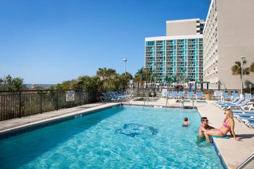 una familia sentada en una piscina en un hotel en Hotel Blue, en Myrtle Beach