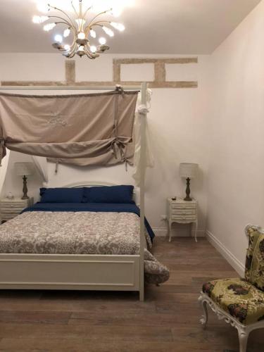 sypialnia z białym łóżkiem i żyrandolem w obiekcie Palazzo Siena De Facendis w mieście Bitonto