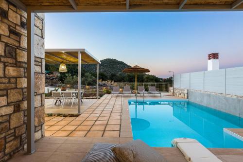 a swimming pool with a patio and a house at Summer Villas Crete in Balíon