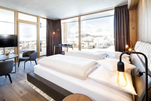 a hotel room with two beds and a large window at Hotel Penzinghof in Oberndorf in Tirol
