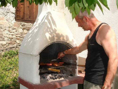 a man cooking food in an outdoor oven at Ferienwohnungen Auhaus in Martello