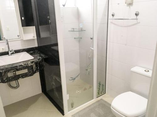 een badkamer met een douche, een toilet en een wastafel bij Edifício Summer Ville in Piratuba