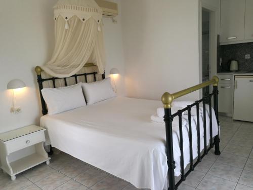 a bedroom with a large white bed with a canopy at Kalimera Studios in Pollonia