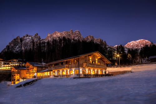 a log cabin in the snow at night at Dolomiti Lodge Alverà in Cortina dʼAmpezzo