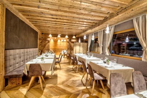 a dining room with white tables and chairs at Dolomiti Lodge Alverà in Cortina dʼAmpezzo