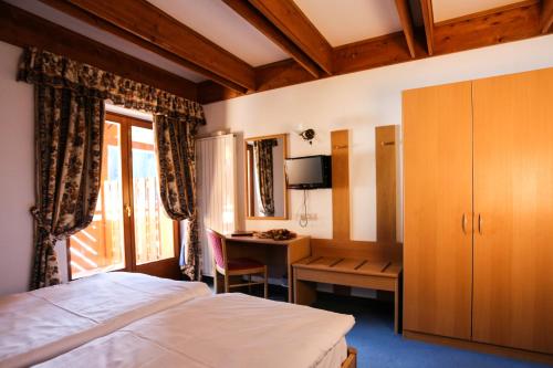 a bedroom with a bed and a desk and a window at Hotel Fortini in Madonna di Campiglio