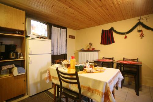a kitchen with a table and a white refrigerator at Eleni's Guesthouse in Palaios Agios Athanasios