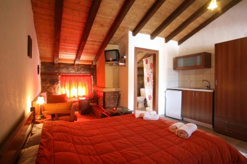 a bedroom with a large red bed and a kitchen at Eleni's Guesthouse in Palaios Agios Athanasios
