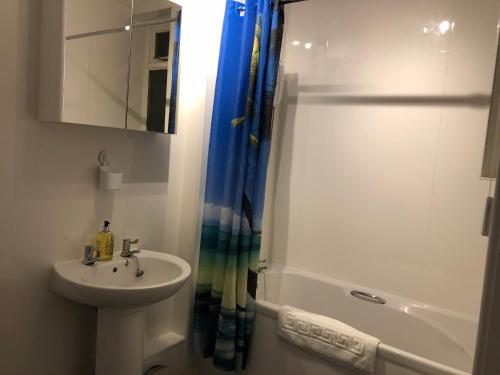 a white bathroom with a sink and a shower at Wellesley Apartment in Leven