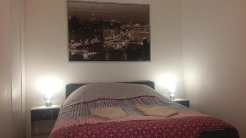 a bedroom with a bed with two lamps and a picture at Appartement avec rez de jardin à Disneyland in Montévrain