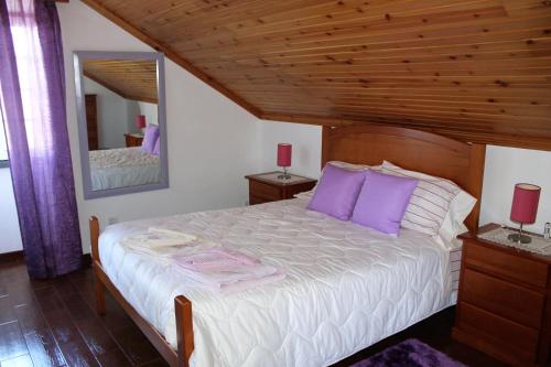 1 dormitorio con 1 cama blanca grande con almohadas moradas en Grande Tranquilidade, en Prainha de Baixo