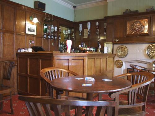a restaurant with a table and chairs and a bar at Ty Newydd Country Hotel in Hirwaun