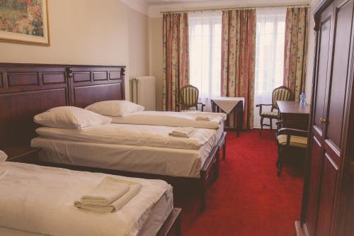 a hotel room with three beds and a desk at Hotel Willa Starosty in Międzyrzecz