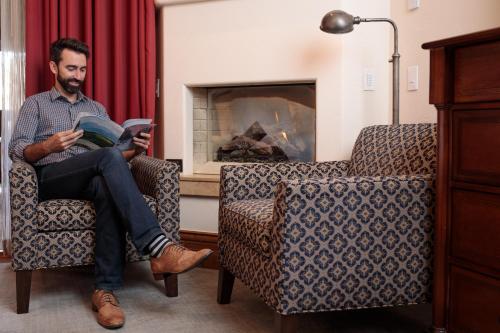 a man sitting in a chair reading a book at The Arrabelle at Vail Square, a RockResort in Vail