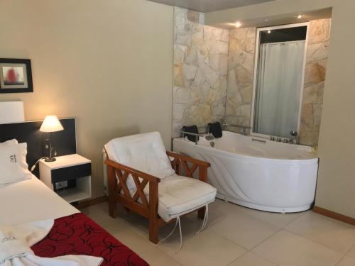 a bathroom with a tub and a chair and a bed at Complejo Pampa in Mar de las Pampas
