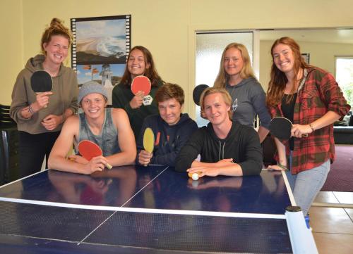 a group of people standing around a ping pong table at Beachcomber Lodge & Backpacker in Kaitaia