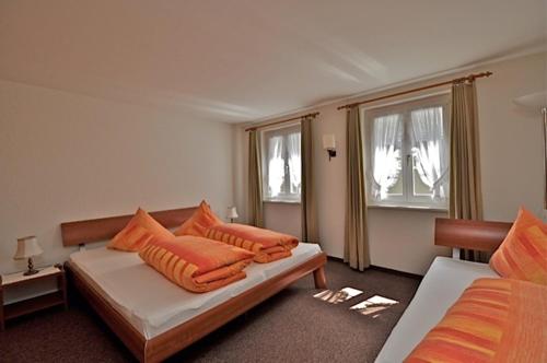 a room with two beds with orange pillows at Gasthaus Skiklub in Andermatt